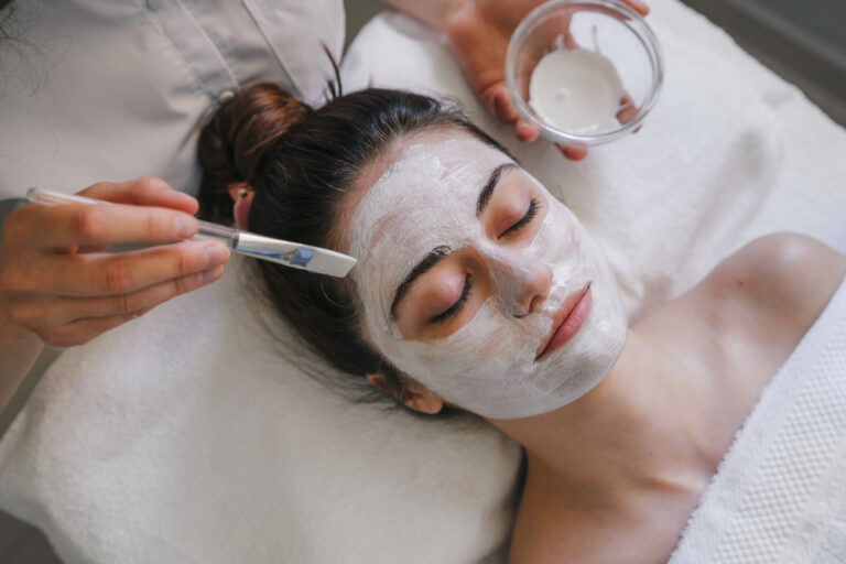 Woman receiving a white facial mask applied with a brush at a spa