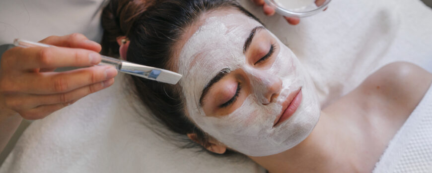 Woman receiving a white facial mask applied with a brush at a spa