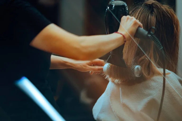 A hairstylist blow-drying and styling hair for a blowout