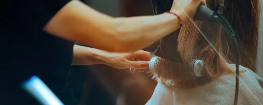 A hairstylist blow-drying and styling hair for a blowout