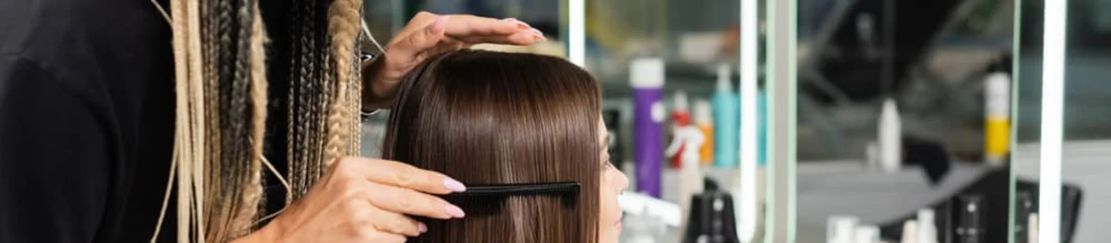 Stylist carefully parts hair to prep for hair extension care and styling session