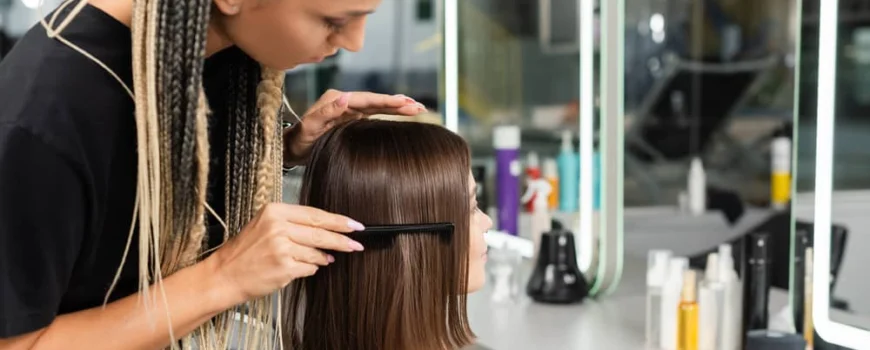Stylist carefully parts hair to prep for hair extension care and styling session