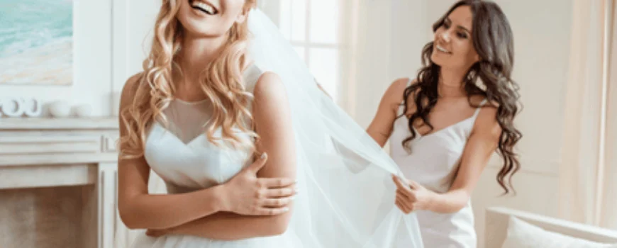 Bridesmaid helps adjust veil while ensuring bride’s bridesmaid blowout hair remains flawless and styled