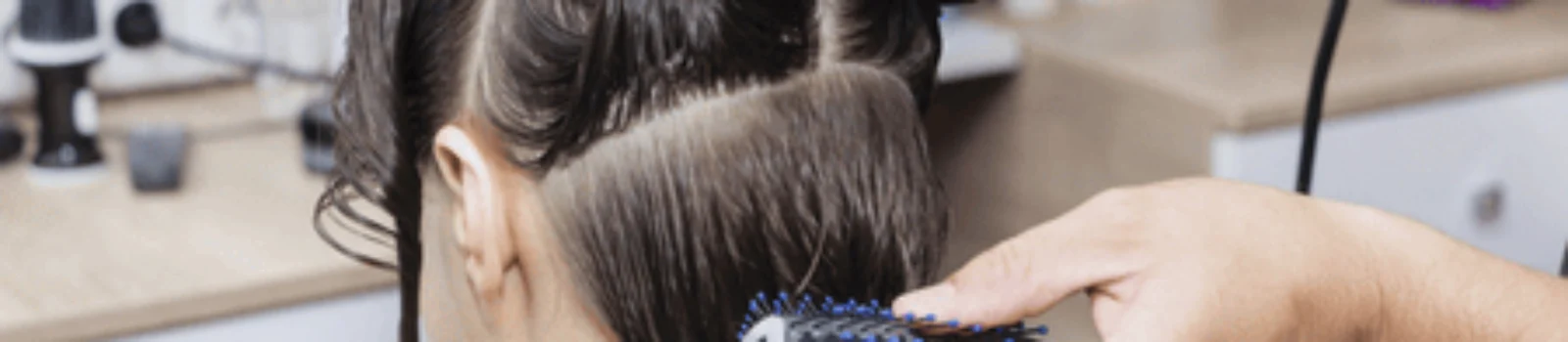 A hairstylist drying sectioned hair with a round brush, showing benefits of a blowout