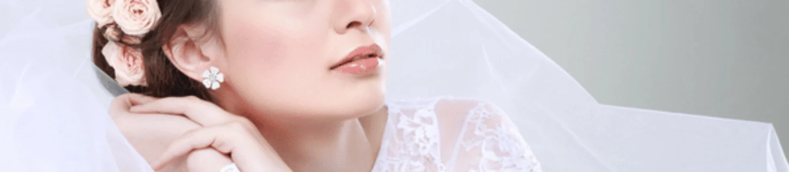 Bride in lace gown with veil and flowers gazes upward, serene portrait before wedding ceremony