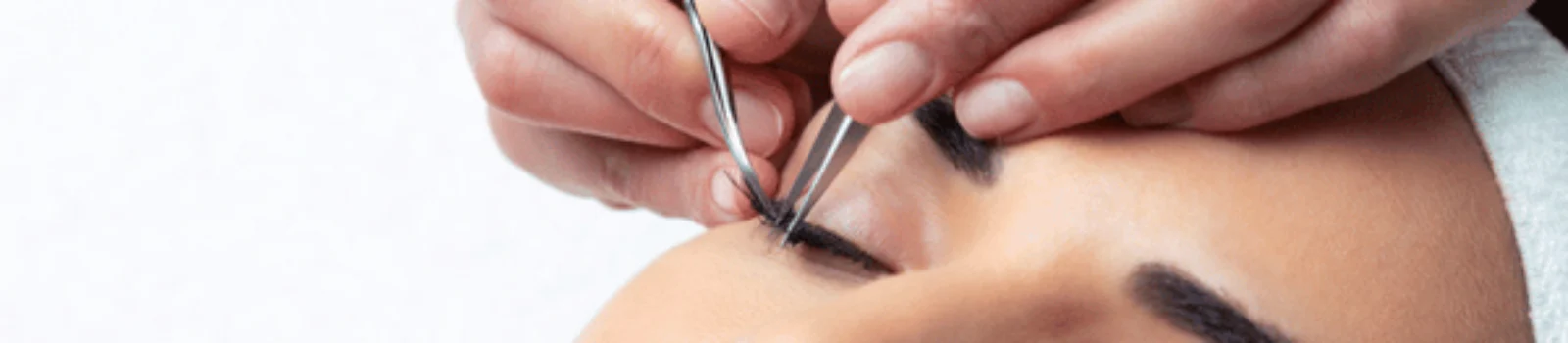 Technician applies lash extensions with tweezers on client while lash and brow services enhance eyes