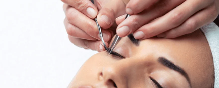 Technician applies lash extensions with tweezers on client while lash and brow services enhance eyes