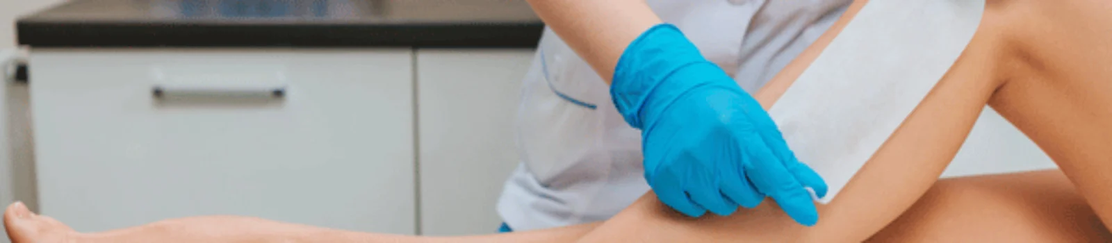 Esthetician applies waxing strip to client leg during body waxing waco appointment in clinic