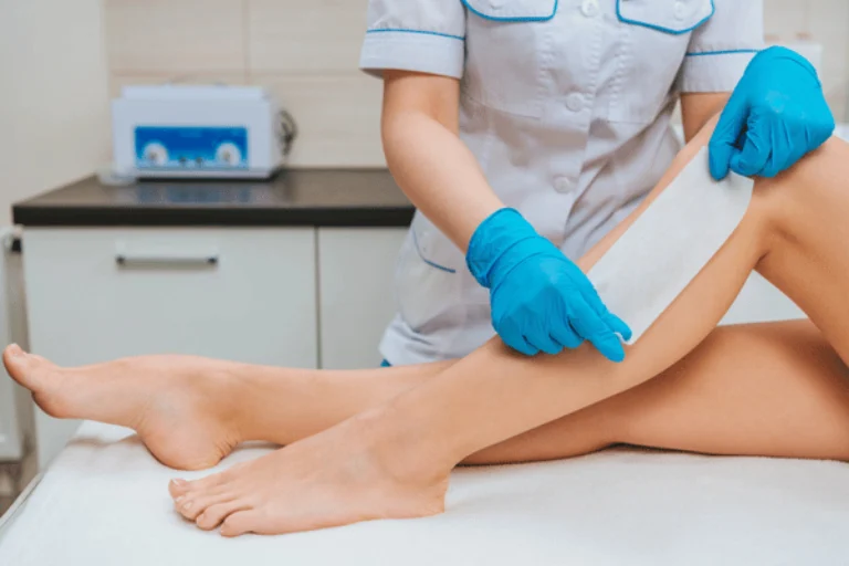 Esthetician applies waxing strip to client leg during body waxing waco appointment in clinic