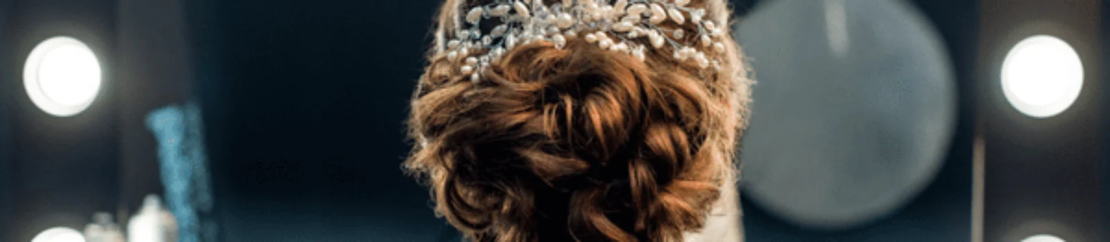 Bride shows elegant updo with jeweled comb in mirror, bridal hair and makeup prep area