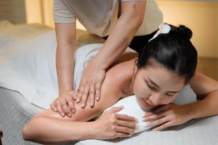 massage in Waco therapist applies shoulder pressure while client relaxes face-down on spa treatment table